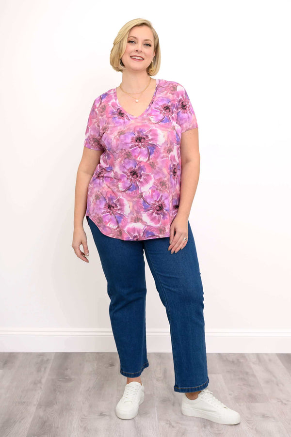 Plus size model in floral v-neck top and jeans, full body front view