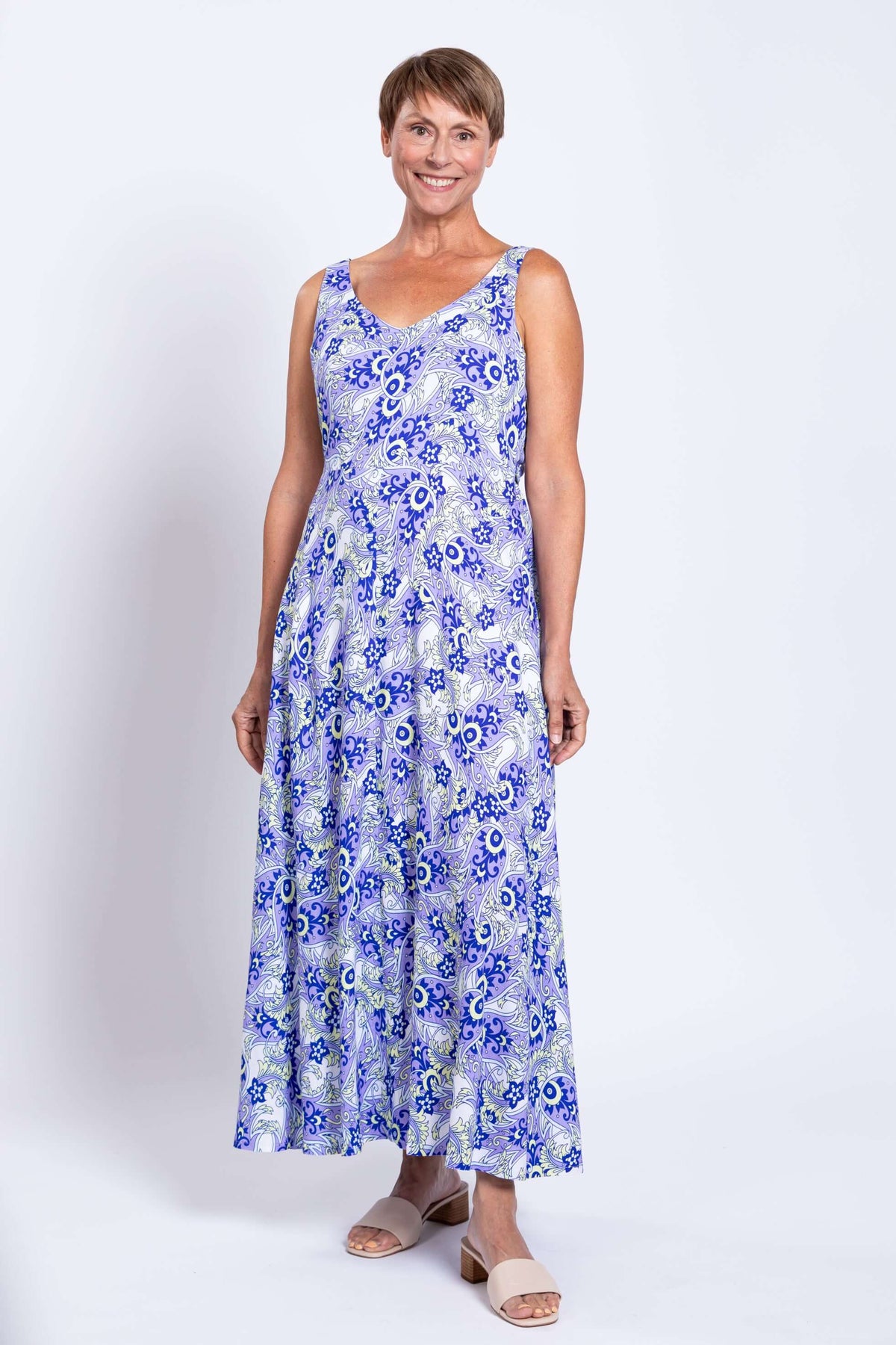 Woman smiling in a blue paisley print sleeveless maxi dress, full front view