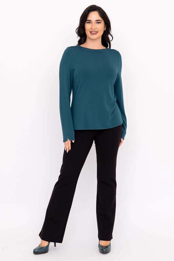 Full body front view of a woman in a teal boat neck top with black pants and teal shoes