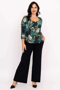 Full body front view of model in dark green floral top with 3/4 sleeves and wide black pants