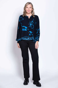Full body front view of model in black batik print blouse and black pants