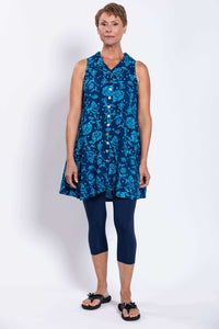 Full body front view of woman in sleeveless blue tank dress with floral print, button-up front, and navy leggings