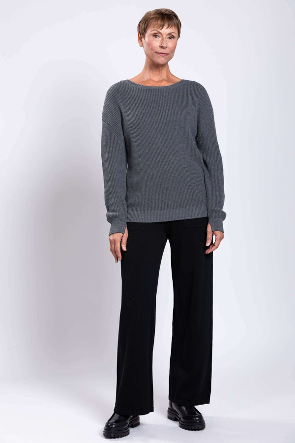 Full body front view of woman in grey cotton sweater and black pants