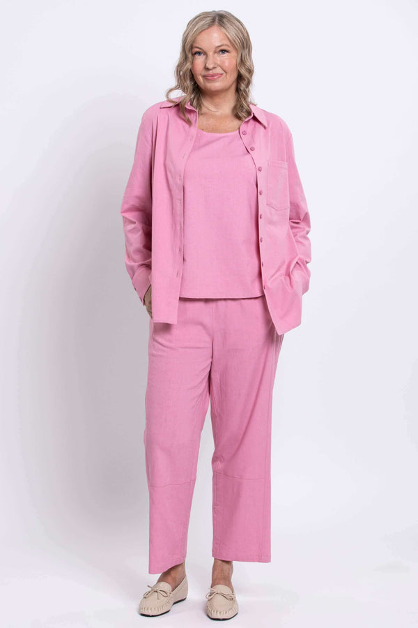 Woman dressed in a pink shirt and pants set, full body front view with beige moccasins