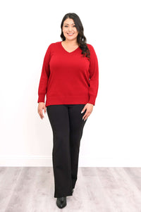 Full body front view of woman in red V-neck sweater and black pants