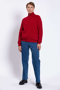 Full body view of person in a red ribbed zip-up sweater, blue jeans, and black boots