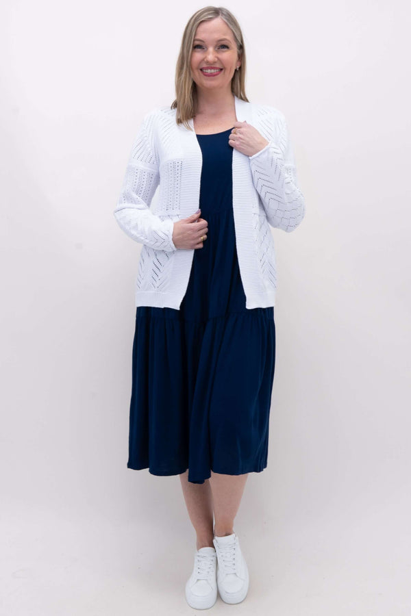 Full body view of woman in white pointelle knit cardigan and navy dress