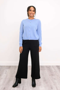 Full body view of a woman in a light blue cashmere cardigan and black wide-leg pants