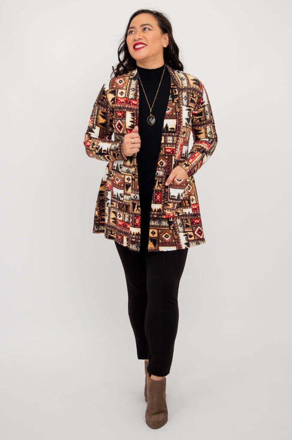 Full body view of woman modeling Pauline patterned jacket, black pants, and ankle boots