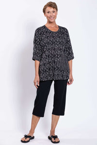 Full body view of a model in the black and white Palace Blouse paired with black capri pants