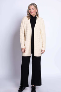 Full body view of a woman modeling a cream cable knit long cardigan sweater