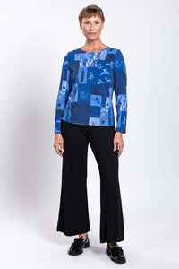 Full body view of a woman in a blue botanical print long sleeve tee and black wide leg pants