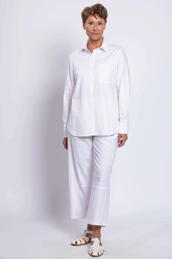 Full body view of a woman in a white button-up shirt and matching white pants