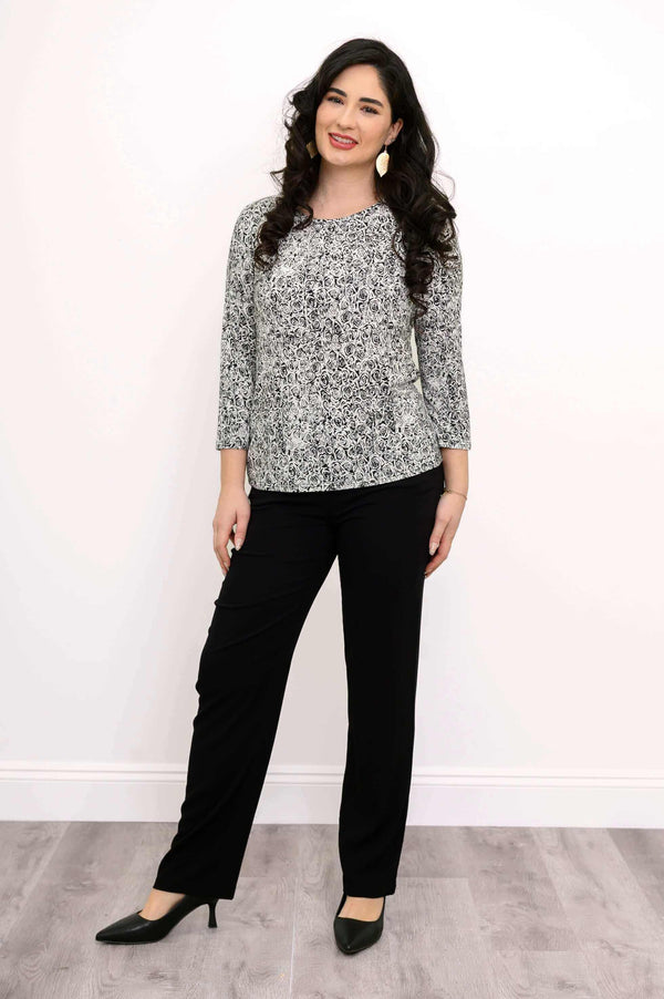 Woman in black pants and black and white floral 3/4 sleeve tee, full body