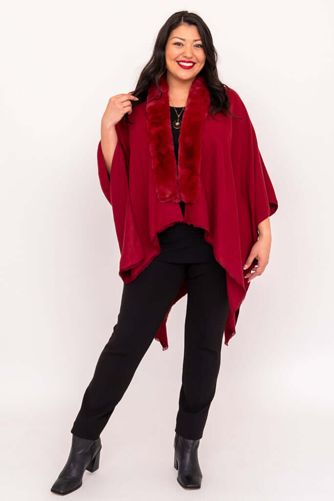 Woman posing in a red faux fur wrap with black pants and boots