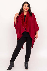 Woman posing in a red faux fur wrap with black pants and boots