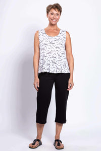 Full body view of woman in white floral peplum tank and black pants