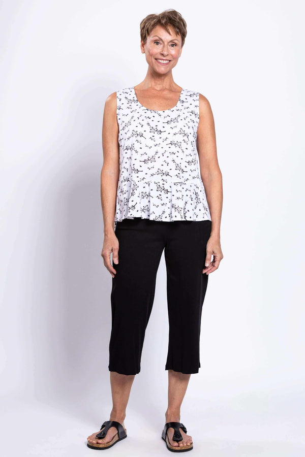 Full body view of woman in white floral peplum tank and black pants