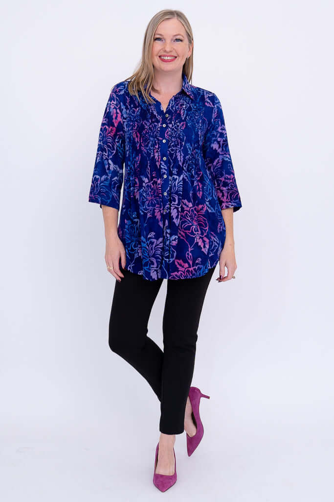 Full body view of woman modeling a blue and purple floral tunic with black pants