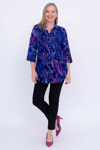 Full body view of woman modeling a blue and purple floral tunic with black pants