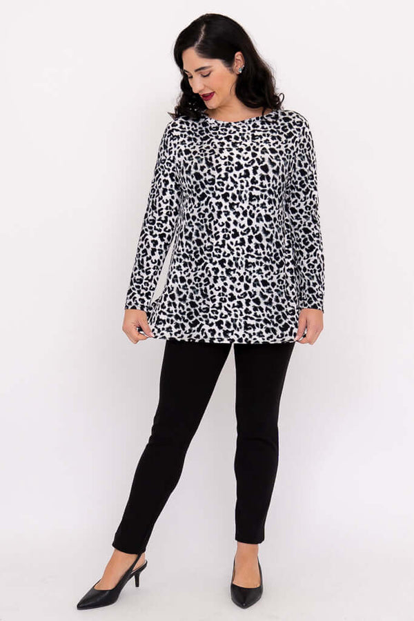 Woman in full body view, modeling a long sleeve animal print tunic top with black pants