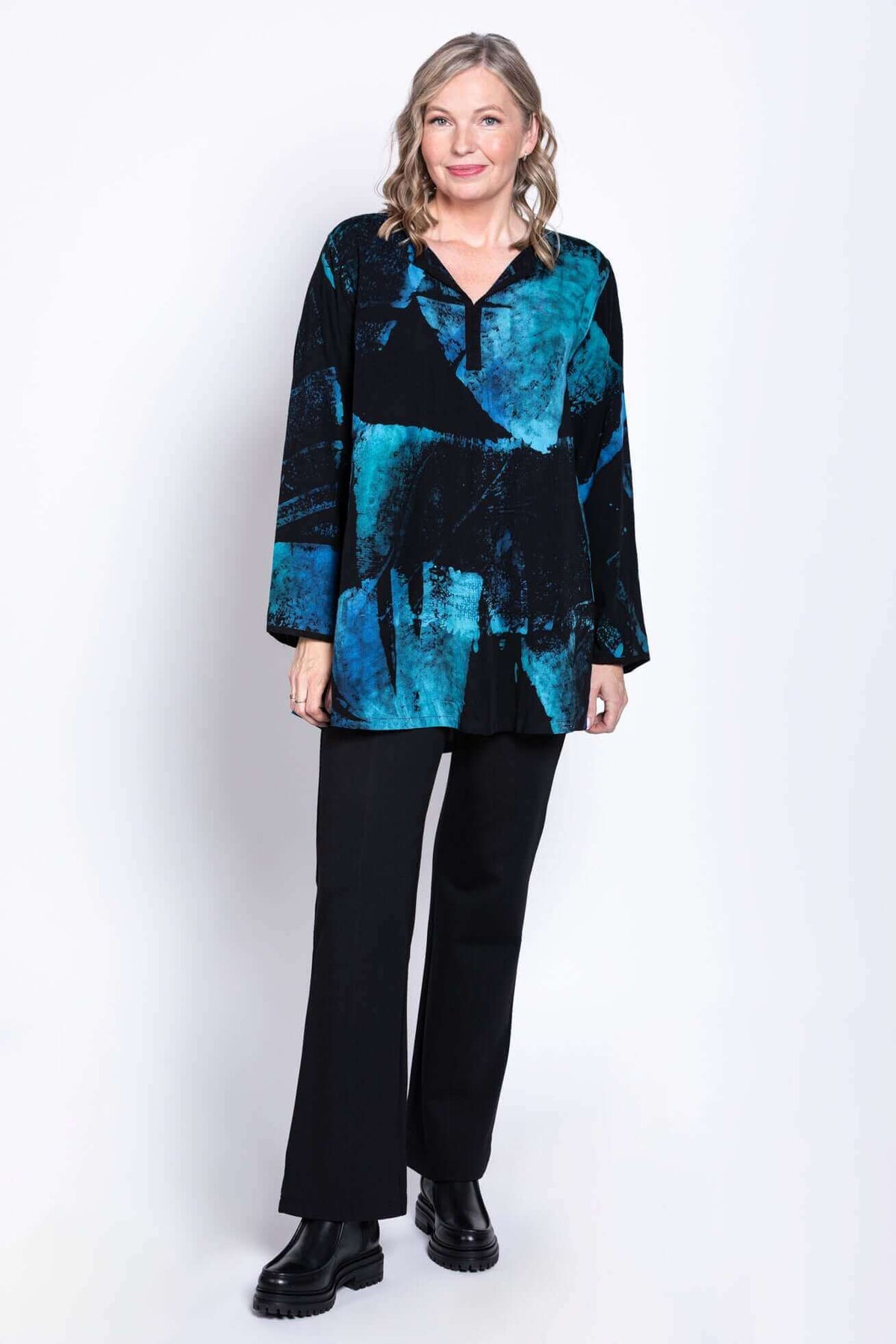 Full body view of model in blue and black batik blouse paired with black pants