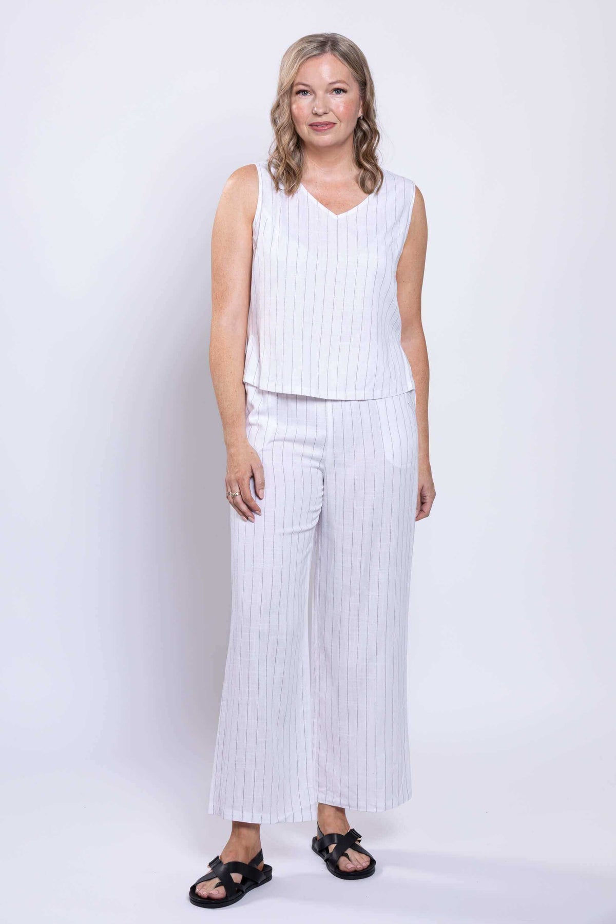 Full body view of woman in a white striped linen tank and matching pants