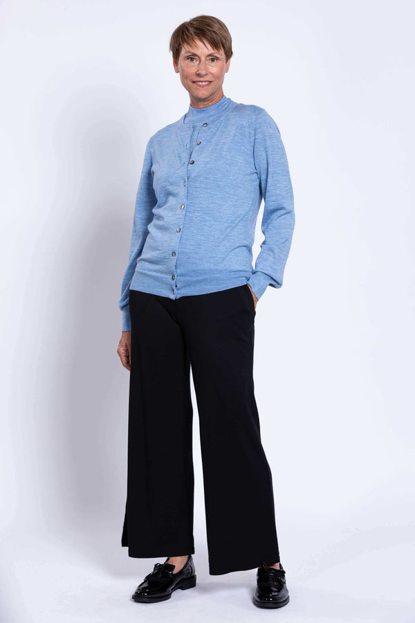 Full body view of woman in light blue cardigan and black wide-leg pants
