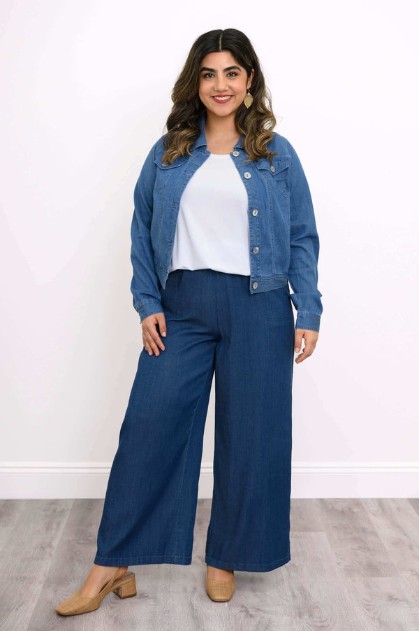 Full body view of a woman wearing a blue denim jacket and matching wide-leg pants