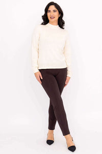 Full body view of woman wearing ivory sweater and brown slim-fit pants