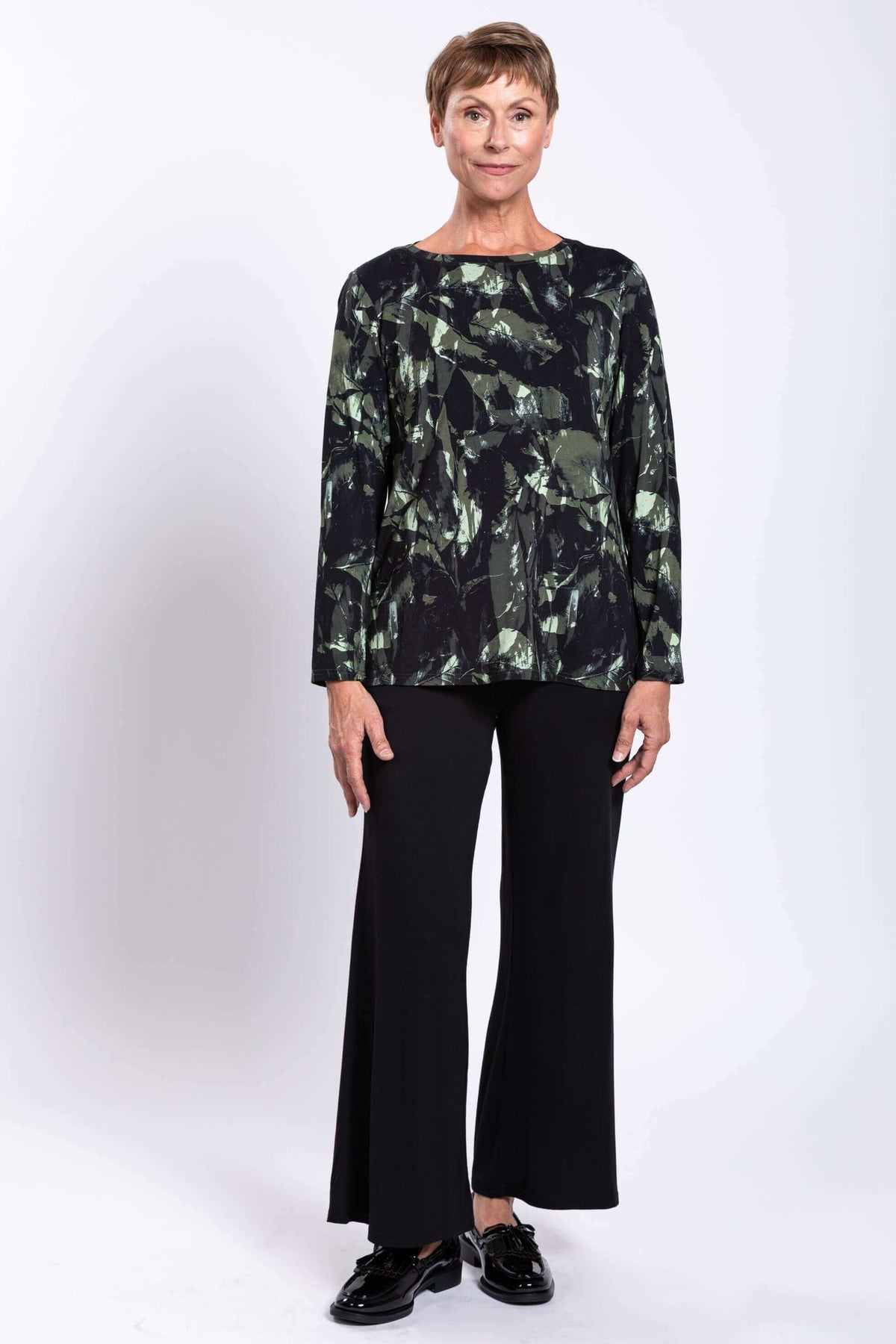 Full body view of woman modeling long sleeve printed top with black pants