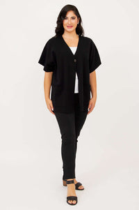 Full body front view of woman modeling a black cardigan with relaxed fit and single button closure