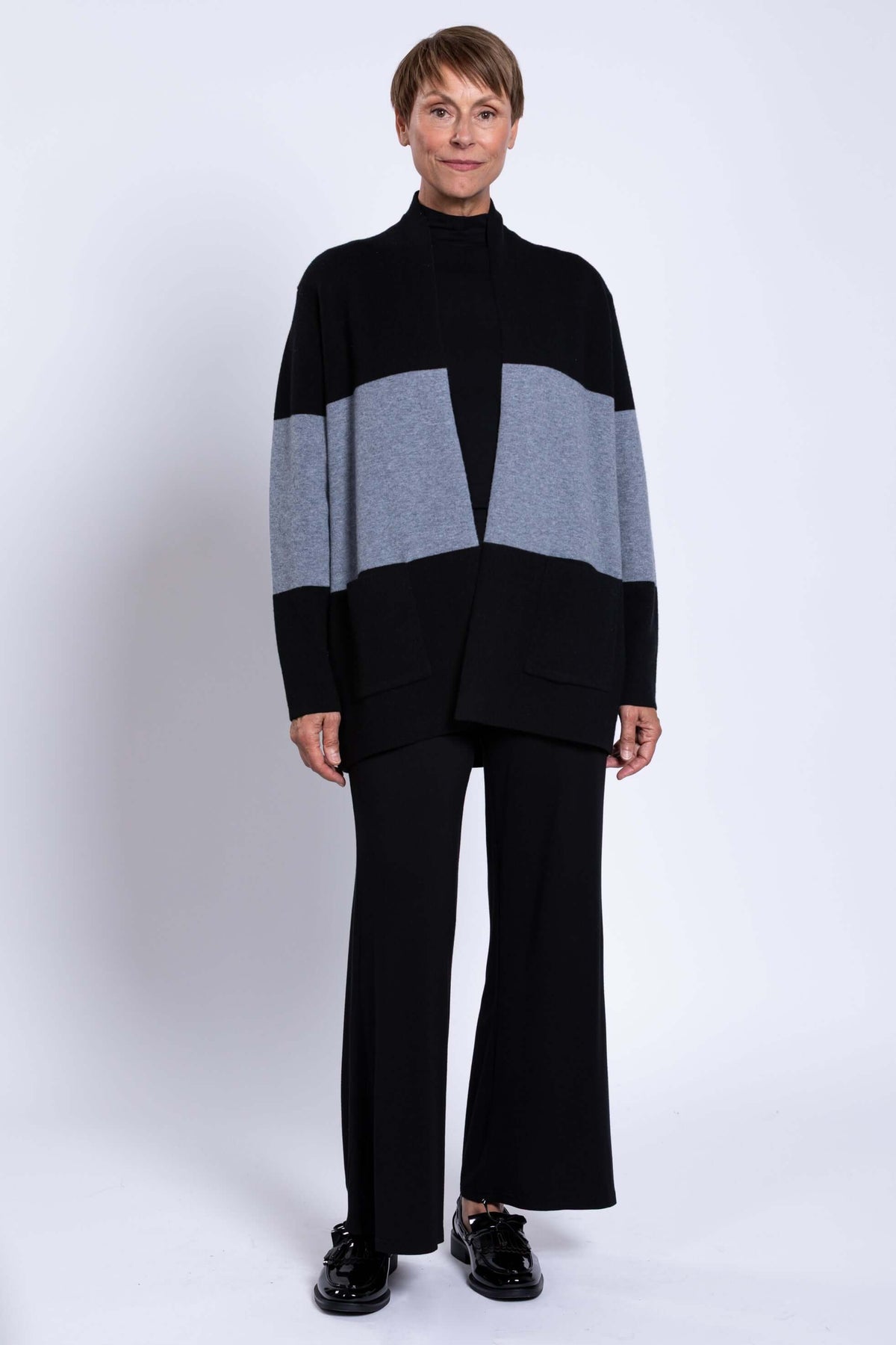 Full body view of model in black and grey colour-block open sweater with wide-leg pants