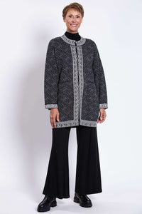 Full body shot of model in black and white trim geometric cardigan and black pants