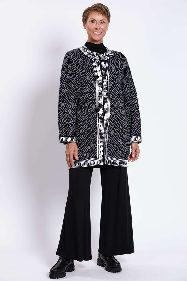 Full body shot of model in black and white trim geometric cardigan and black pants