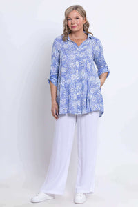 Full body view of woman in blue floral oversized tunic and white pants