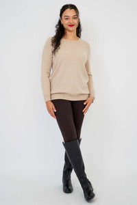 Full body view of woman in beige sweater, brown pants, and black boots