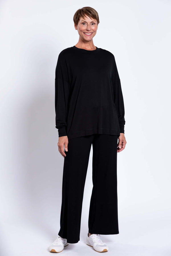 Full body view of woman in black crew neck top and matching wide-leg pants, front view