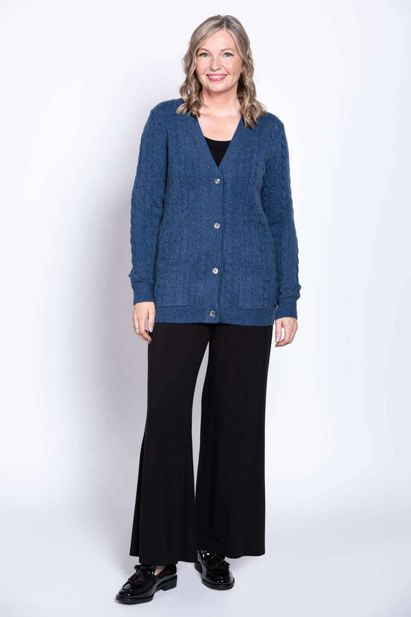 Full body view of woman in blue cable knit cardigan and black wide-leg pants