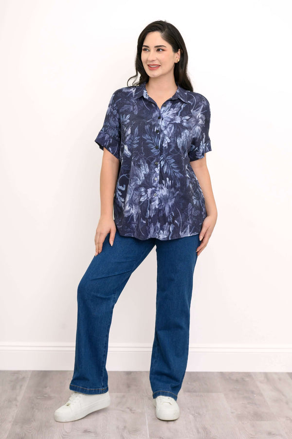 Full body view of woman in blue floral blouse and blue jeans, standing and smiling