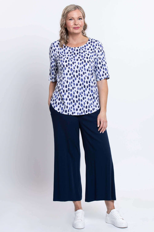 Full body view of woman in navy polka dot blouse and wide leg navy pants
