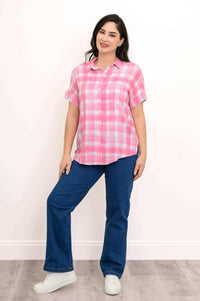 Full body view of woman in pink plaid blouse with blue jeans and white sneakers
