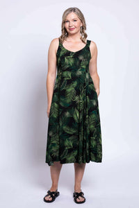 Full body view of a woman in a sleeveless green leaf print dress with pockets