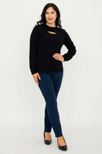 Full body view of model in black cutout sweater and navy pants, hands on hip