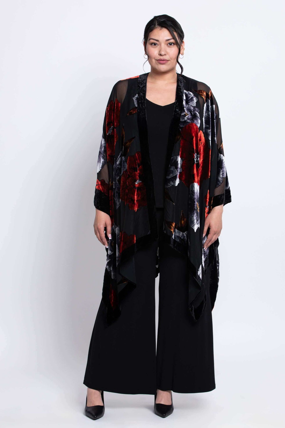 Woman standing in a black floral kimono wrap with red and grey flowers, full front view