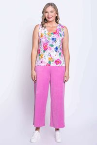 Full front view of a woman in a floral tank top with pink pants and white sneakers