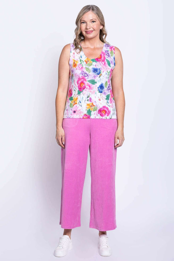 Full front view of a woman in a floral tank top with pink pants and white sneakers