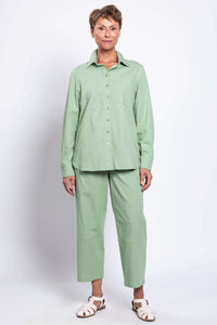 Full frontal view of a woman in a sage green button-up shirt and matching straight-leg pants
