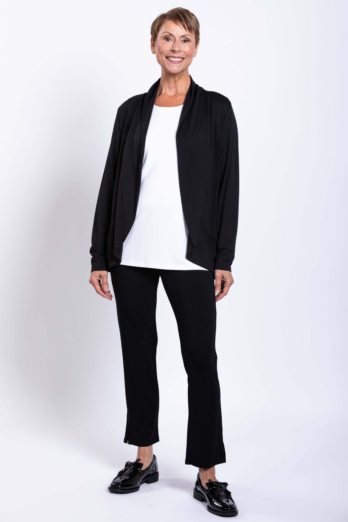 Woman standing in black French Terry jacket, white top, and black pants, full front view