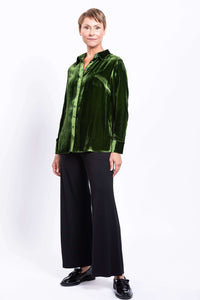 Full front view of model in green silk velvet blouse and black pants